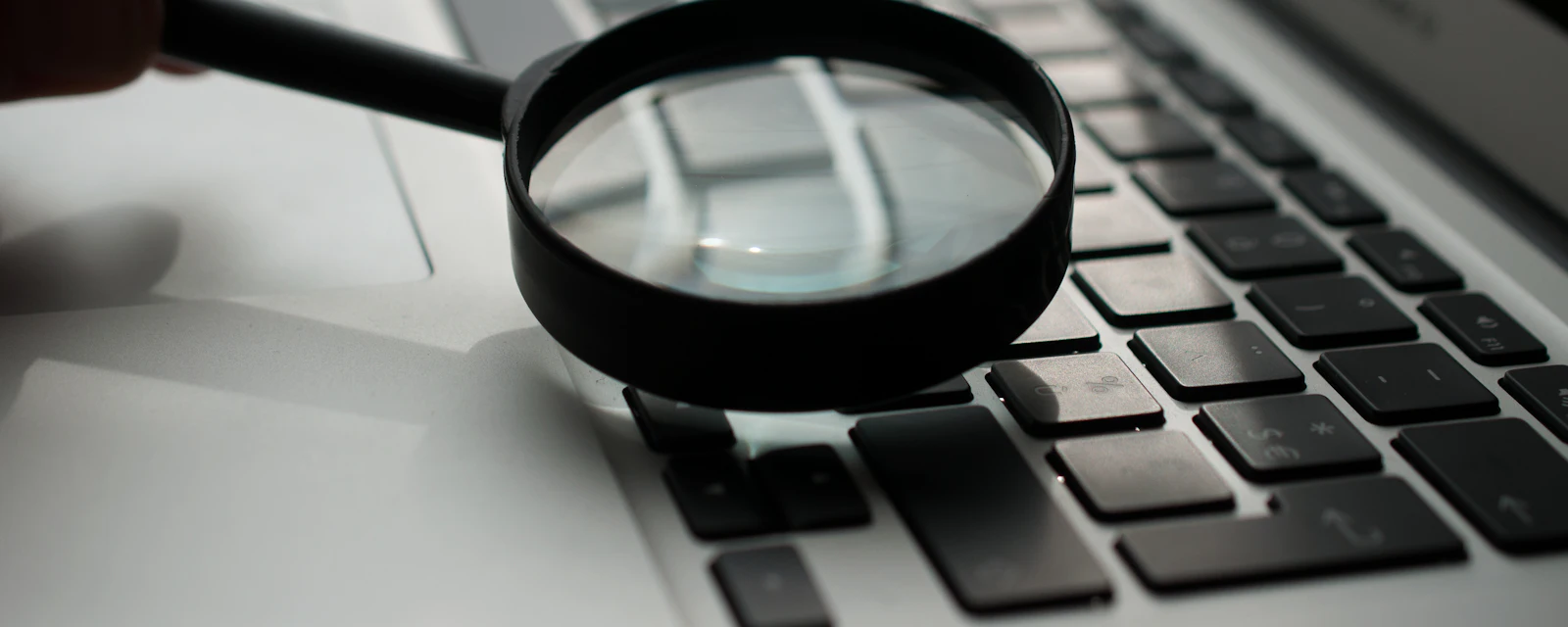 A magnifying glass resting on a laptop keyboard